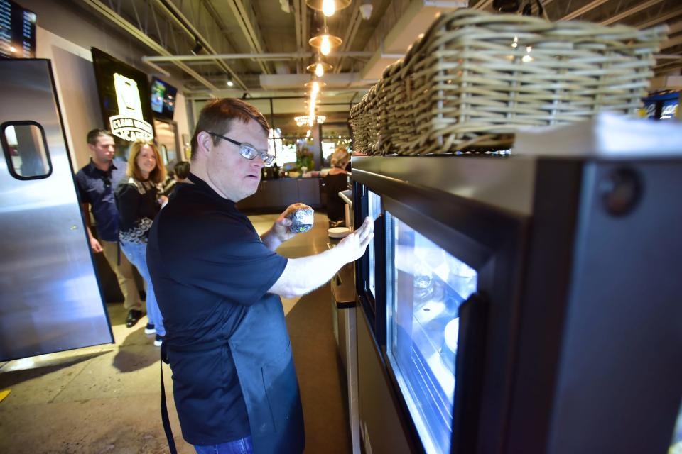 Robby Brooks, picks a muffin out of the display show case at "Clean Water Cafe" public coffee house that is staffed by special-needs adults at their big converted warehouse facility in Liquid Church located in Parsippany, Wednesday on 09/08/22.