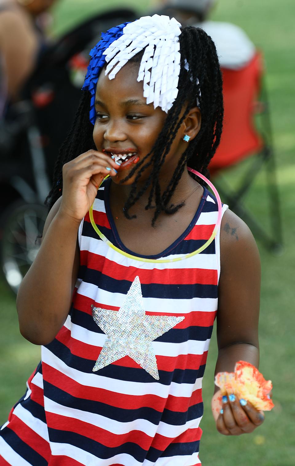 Guests took the opportunity to celebrate the Fourth of July at Greenville's Unity Park.  Miracle Gould, 6, of Greenville dressed in Red White and Blue eats her treat at the park. 