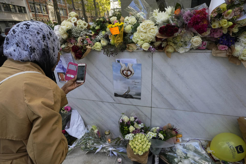 A woman takes a picture of a poster reading " Rest in peace" outside the building where the body of 12-year-old schoolgirl was discovered in a trunk, in Paris, Wednesday, Oct. 19, 2022. France has been "profoundly shaken" by the murder of a 12-year-old schoolgirl, whose body was found in a plastic box, dumped in a courtyard of a building in northeastern Paris, the government spokesman Olivier Veran said on Wednesday. (AP Photo/Michel Euler)