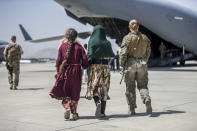 In this image provided by the U.S. Marine Corps, a Marine with the 24th Marine Expeditionary Unit walks with a family during ongoing evacuations at Hamid Karzai International Airport, Kabul, Afghanistan, Tuesday, Aug. 24, 2021. (Sgt. Samuel Ruiz/U.S. Marine Corps via AP)