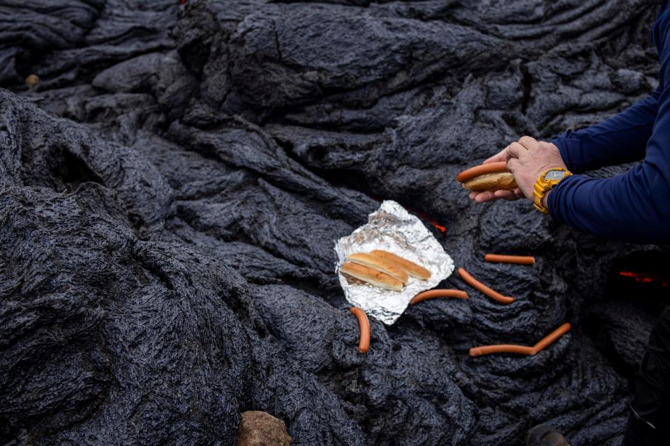 A man prepares hot dogs at the volcanic site on the Reykjanes Peninsula following Friday's eruption in Iceland March 21, 2021. Picture taken March 21, 2021.