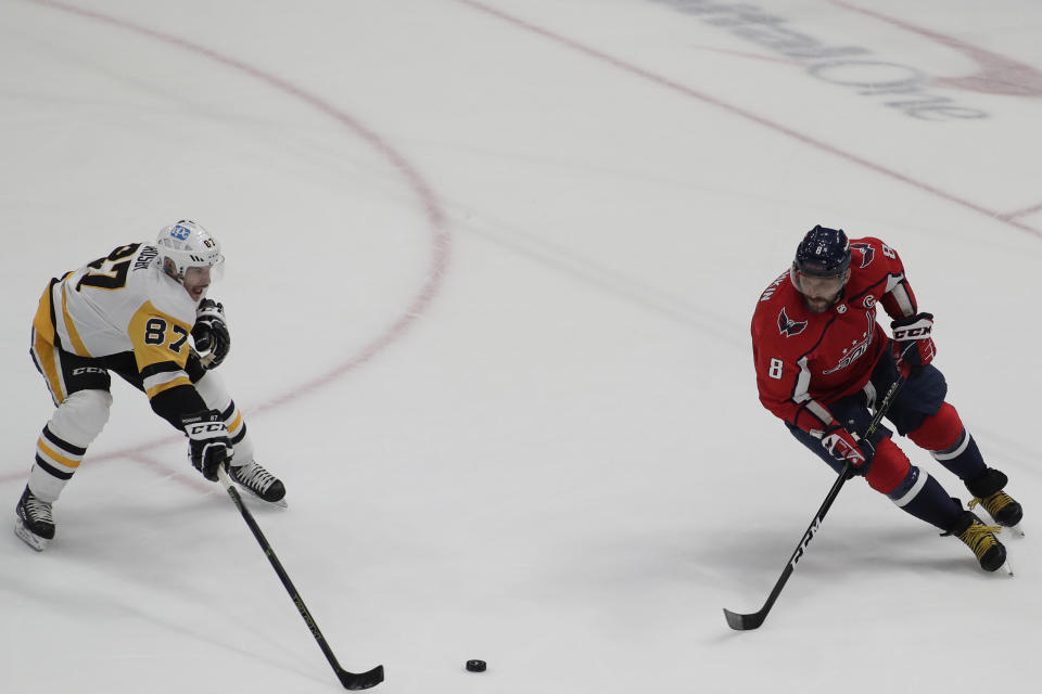 Pittsburgh Penguins' Sidney Crosby (87) reaches for the puck as Washington Capitals' Alex Ovechkin (8) defends during the third period of an NHL hockey game, Friday, Dec. 10, 2021, in Washington. (AP Photo/Luis M. Alvarez)