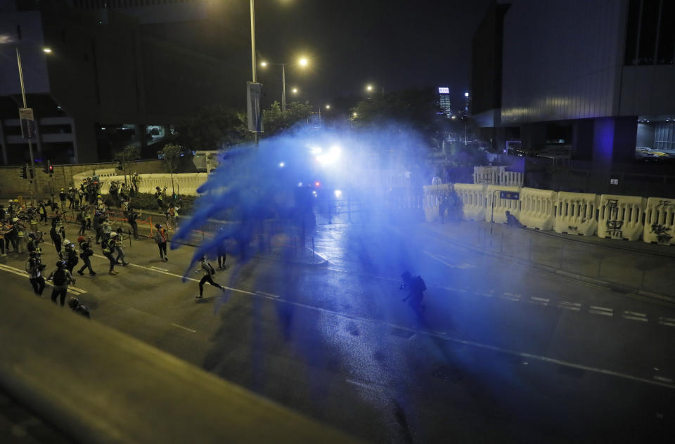 Police fire blue-colored water on protestors in Hong Kong, Saturday, Sept. 28, 2019. Protesters streamed onto a main road nearby and some targeted government buildings that were barricaded. Police initially used a hose to fire pepper spray after some demonstrators threw bricks. A water cannon truck later fired a blue liquid, used to identify protesters, after protesters lobbed gasoline bombs through the barriers. (AP Photo/Kin Cheung)
