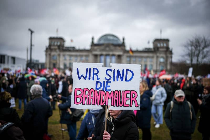 Demonstrators hold up placards suring a demonstration of the alliance "We are the firewall" for democracy and against right-wing extremism in front of the Reichstag building in Berlin. Kay Nietfeld/dpa