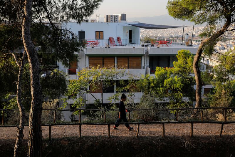 A woman walks on Lycabettus hill as apartments are seen in the background, in Athens