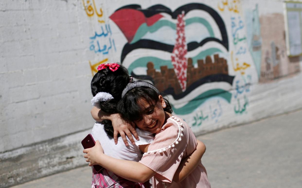 Palestinian students hug after receiving their certificates as preventive measures against the coronavirus disease - REUTERS