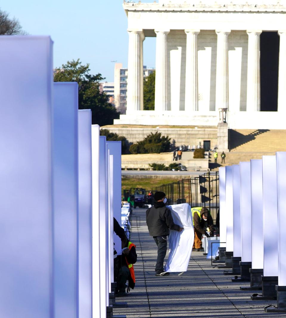 Workers dismantle the fabric pillars of light used near the Lincoln Memorial, in the background, during inauguration ceremonies for President Jose Biden the day before, on Jan 21, 2021, in Washington, D.C.