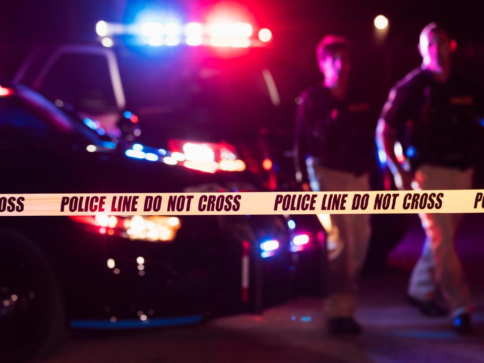 Two police officers behind crime scene tape - stock photo