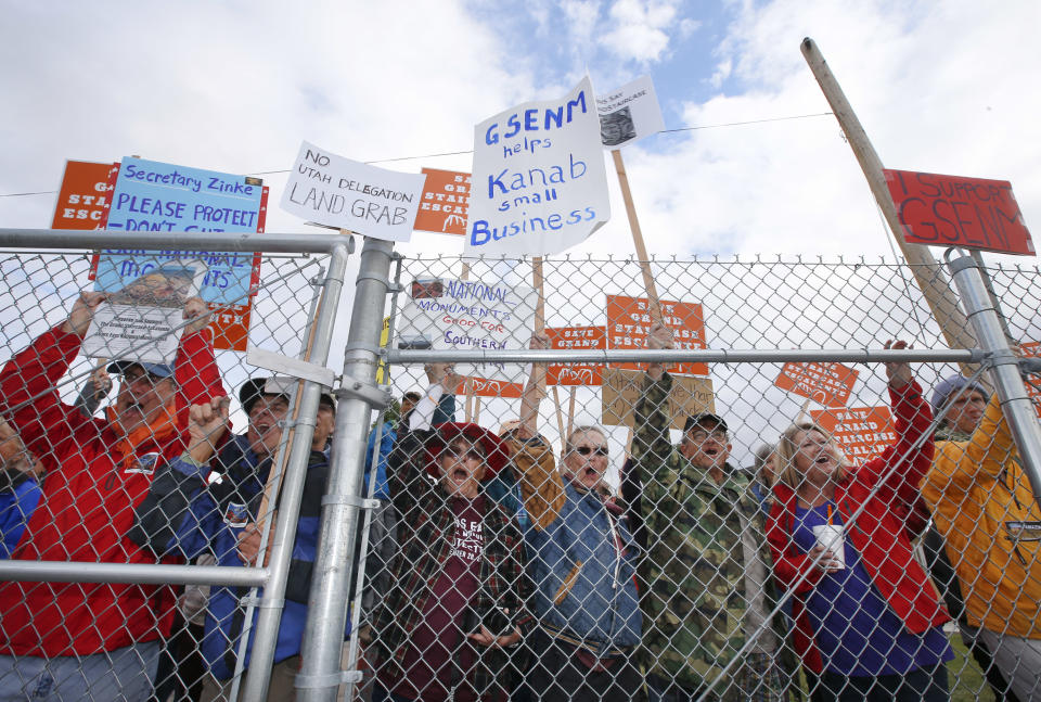 Protesters hold signs and chant behind a security fence as U.S. Secretary of the Interior Ryan Zinke arrives at Kanab Airport for departure on May 10, 2017, in Kanab, Utah. (Photo: George Frey/Getty Images)