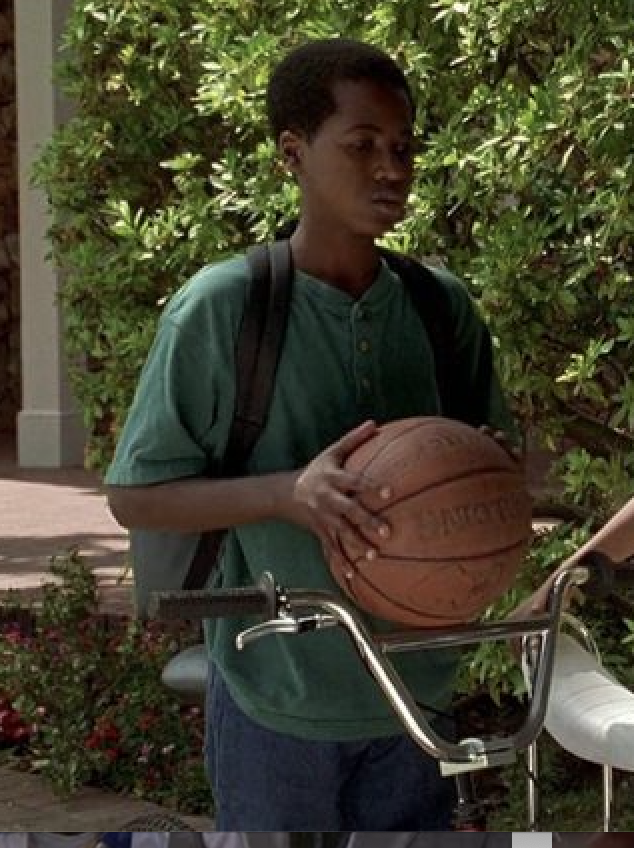 Glenndon wearing a shirt and jeans and a backpack and holding a basketball