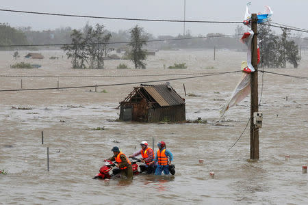 People recover motorbikes from a flooded fields while the Doksuri storm hits in Ha Tinh province, Vietnam September 15, 2017. REUTERS/Kham