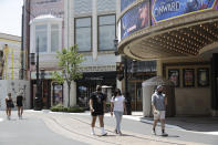 People walk in a mostly empty The Grove shopping center Wednesday, May 27, 2020, in Los Angeles. California moved to further relax its coronavirus restrictions and help the battered economy. Retail stores, including those at shopping malls, can open at 50% capacity. (AP Photo/Marcio Jose Sanchez)