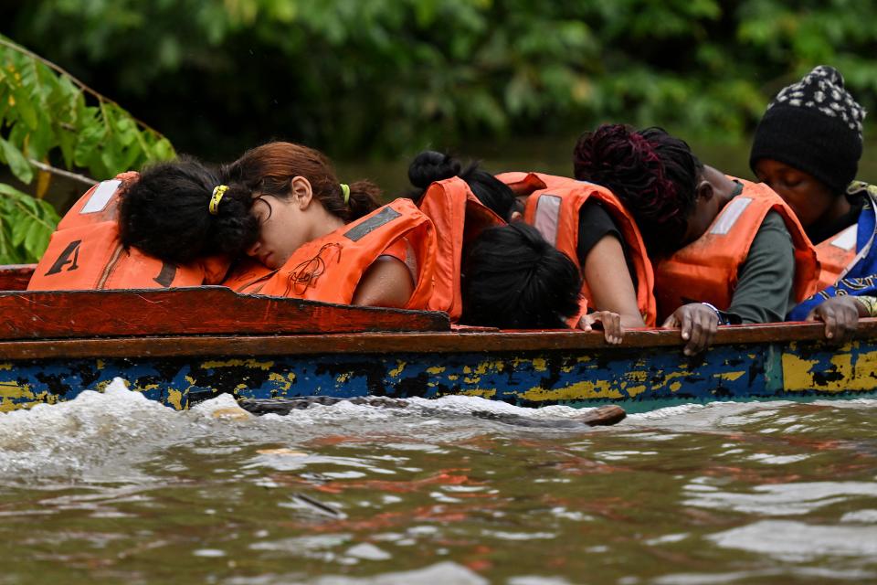 Venezuelan migrants sleep during their travel in a pirogue to Meteti, through the Chucunaque river from Canaan Membrillo village, the first border control of the Darien Province in Panama, on Oct. 12, 2022.