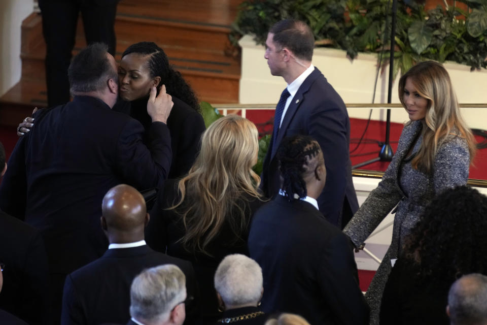 Country music star Garth Brooks and former first lady Michelle Obama embrace at the end of a tribute service for former first lady Rosalynn Carter, at the Glenn Memorial Church, in Atlanta, Tuesday, Nov. 28, 2023. Pictured right is former first lady Melania Trump. (AP Photo/Andrew Harnik)