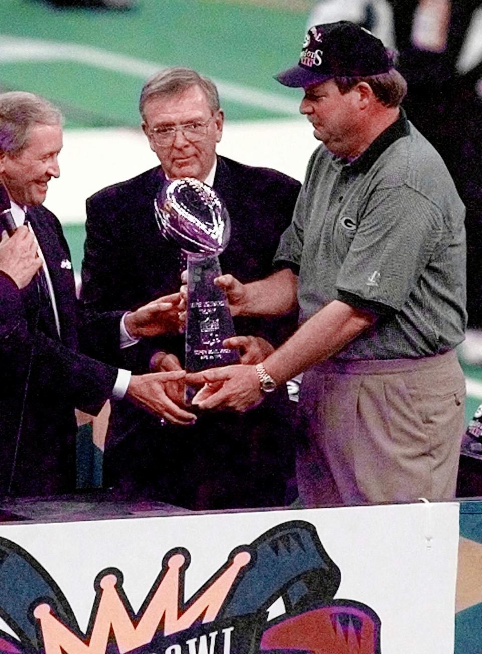 Green Bay Packers President Robert Harlan, left, General Manager Ron Wolf, and coach Mike Holmgren, right, receive the Lombardi Trophy after beating the New England Patriots 35-21 in Super Bowl XXXI  Jan. 26, 1997, in New Orleans. The Packers won 35-21. (AP Photo/Lenny Ignelzi)