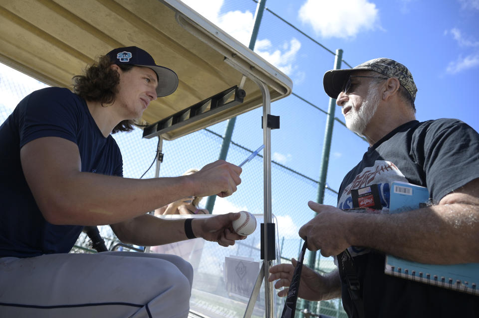 Tampa Bay Rays pitcher Tyler Glasnow, left, signs an autograph for a fan during the first practice for pitchers and catchers at spring training baseball camp, Wednesday, Feb. 15, 2023, in Kissimmee, Fla. (AP Photo/Phelan M. Ebenhack)