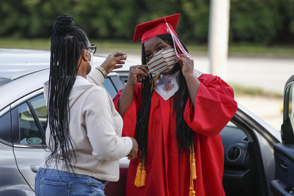 Graduate student Tyleah Whitlow puts a mask on her face as she arrives to pick up her diploma at Bradley-Bourbonnais Community High School on May 6, 2020 in Bradley, Illinois. - A speech by Barack Obama, a photo finish at Daytona, or a wild, livestreamed party in the family living room? Americans are dreaming up creative ways to celebrate their graduates, deprived of traditional diploma ceremonies by the coronavirus pandemic.High school and university graduation ceremonies are much-anticipated rites of passage in the United States, almost "as important as weddings or births," says 29-year-old Trent Johnson.  So when, after four years of medical school, he received an email telling him that his university, Ohio State, was cancelling the ceremony because of the pandemic, he was overwhelmed. (Photo by KAMIL KRZACZYNSKI / AFP) (Photo by KAMIL KRZACZYNSKI/AFP via Getty Images)