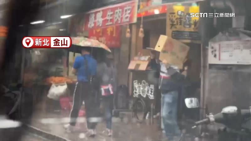 新北市金山降下大雨，有民眾沒有雨具向一旁店家要紙箱擋雨。