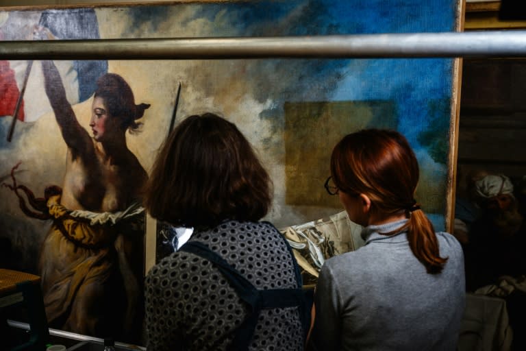 Des restaurateurs travaillent sur le tableau "La liberté guidant le peuple" d'Eugène Delacroix, dans un laboratoire du Musée du Louvre à Paris, le 28 février 2024 (Dimitar DILKOFF)
