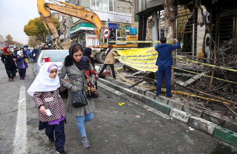 FILE PHOTO: People walk near a burnt bank, after protests against increased fuel prices, in Tehran