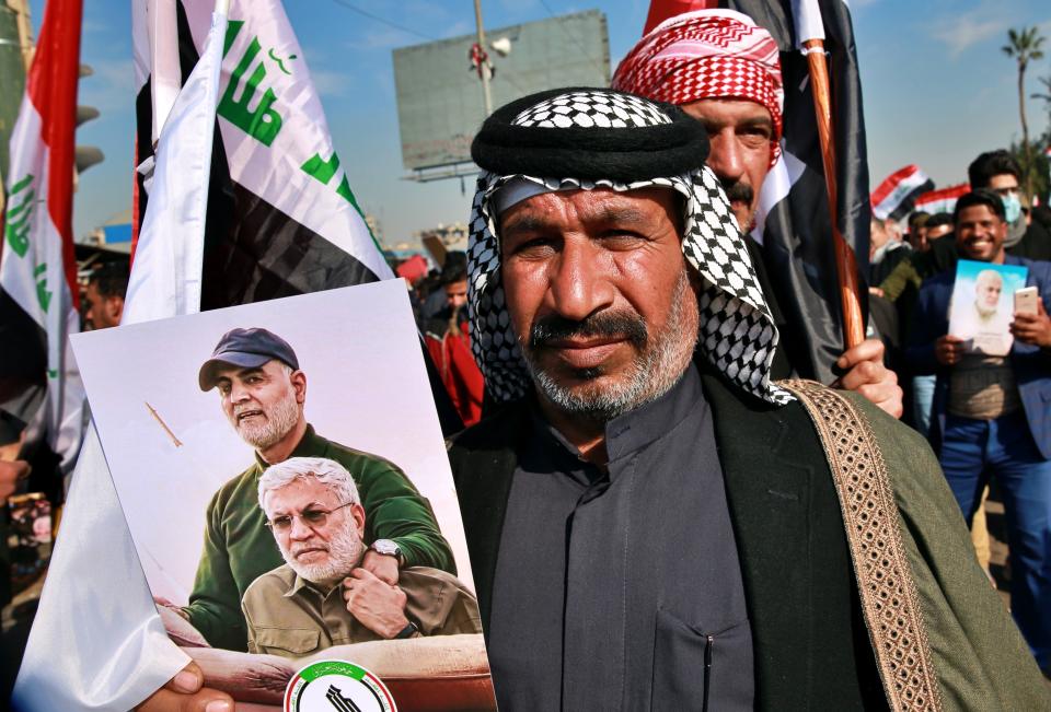Supporters of the Popular Mobilization Forces hold a posters of Abu Mahdi al-Muhandis, deputy commander of the Popular Mobilization Forces, front, and General Qassem Soleimani, head of Iran's Quds force during a protest, in Tahrir Square, Iraq, Sunday, Jan. 3, 2021. Thousands of Iraqis converged on a landmark central square in Baghdad on Sunday to commemorate the anniversary of the killing of Soleimanil and al-Muhandis in a U.S. drone strike. (AP Photo/Khalid Mohammed)