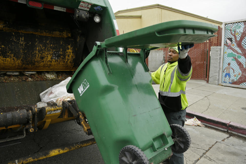 In this photo taken Thursday, Oct. 27, 2016, apprentice garbage man Corey Lever collects trash outside a school in Oakland, Calif. A new partnership between Waste Management of Alameda County Inc., the nonprofit Oakland Civicorps and unions gives young adults, often high school dropouts from low-income communities, a chance to become teamster drivers after two years of training. Like most little boys, Lever liked trucks, but his favorite was always the garbage truck. (AP Photo/Eric Risberg)