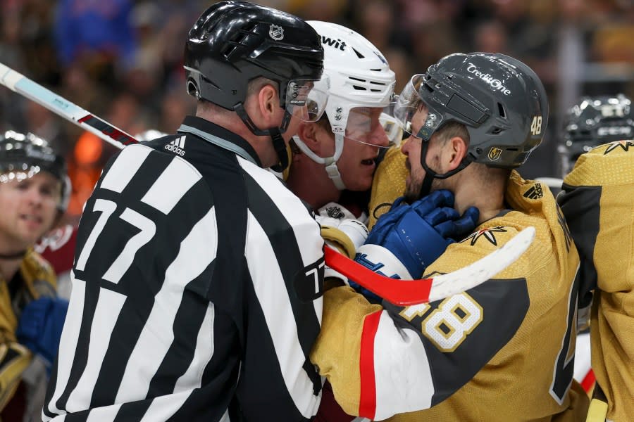 Linesman Caleb Apperson (77) attempts to break up a fight between Colorado Avalanche defenseman Josh Manson, center, and Vegas Golden Knights center Tomas Hertl (48) during the second period of an NHL hockey game Sunday, April 14, 2024, in Las Vegas. (AP Photo/Ian Maule)