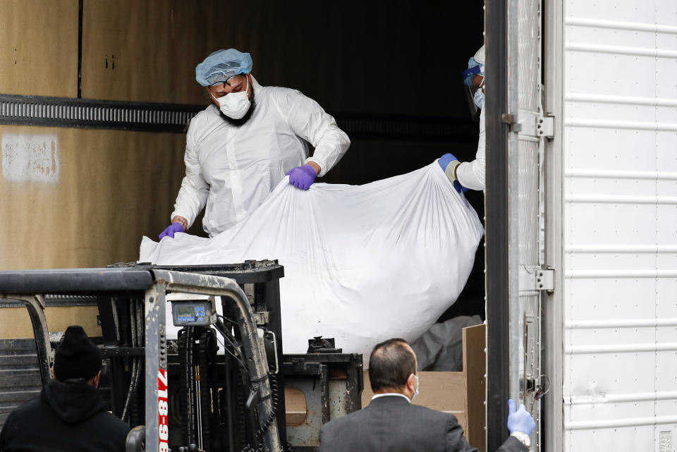 A body wrapped in plastic is loaded onto a refrigerated container truck used as a temporary morgue on Tuesday. Source: AP/John Minchillo