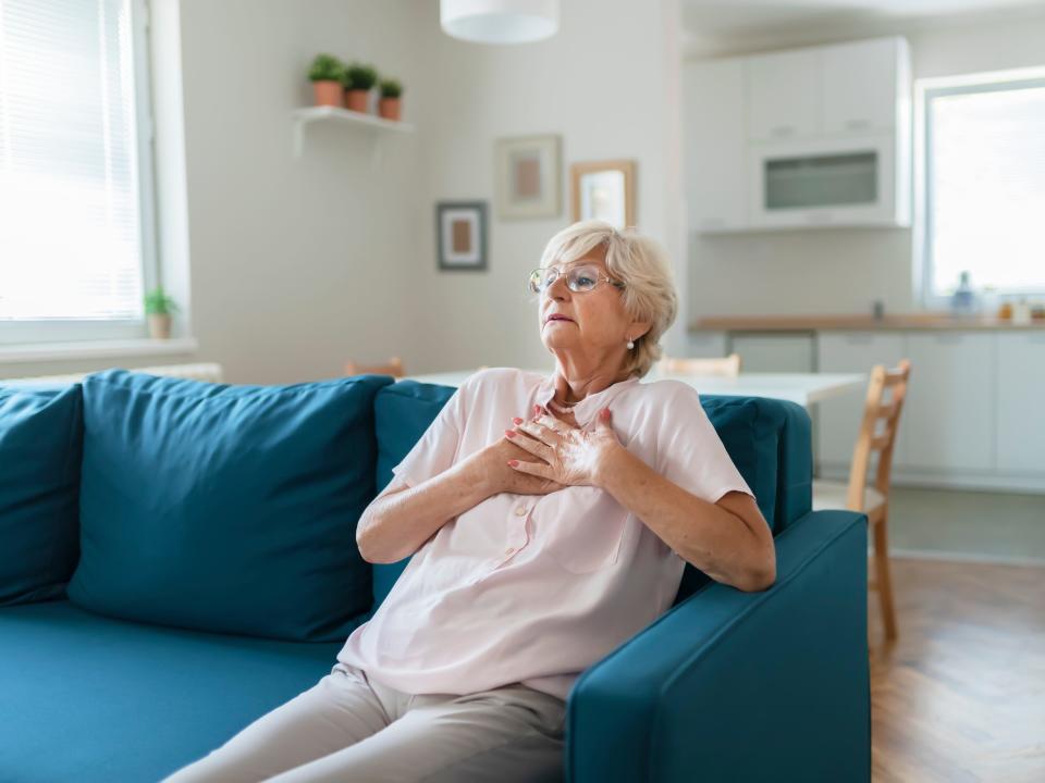 A stock photo of an elderly woman experiencing chest pain.