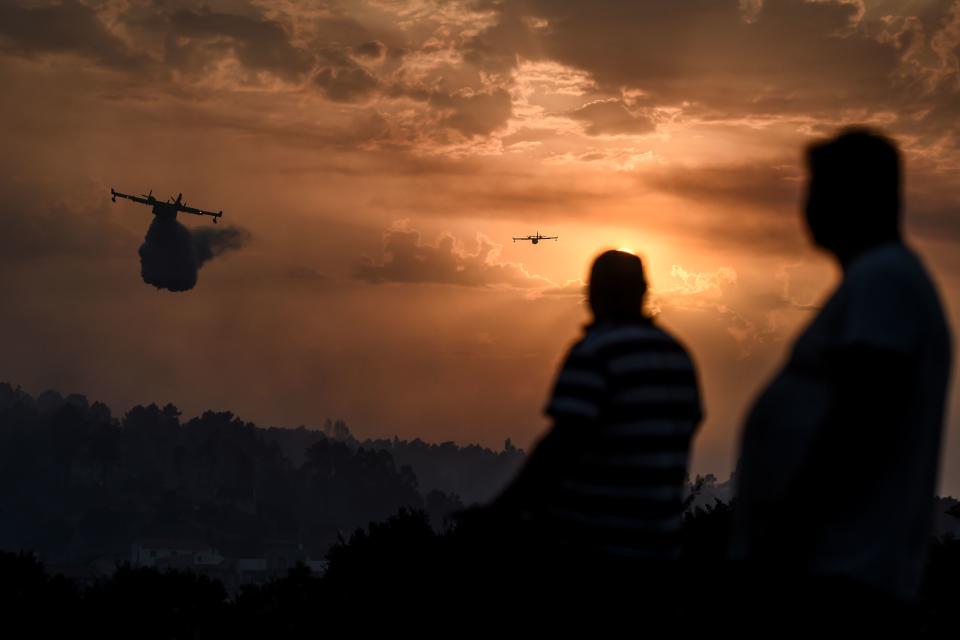 Villagers watch fire squads drop water over a wildfire as the sun sets in Chaveira in Macao in central Portugal on July 22, 2019. (Photo: Patricia De Melo Moreira/AFP/Getty Images)