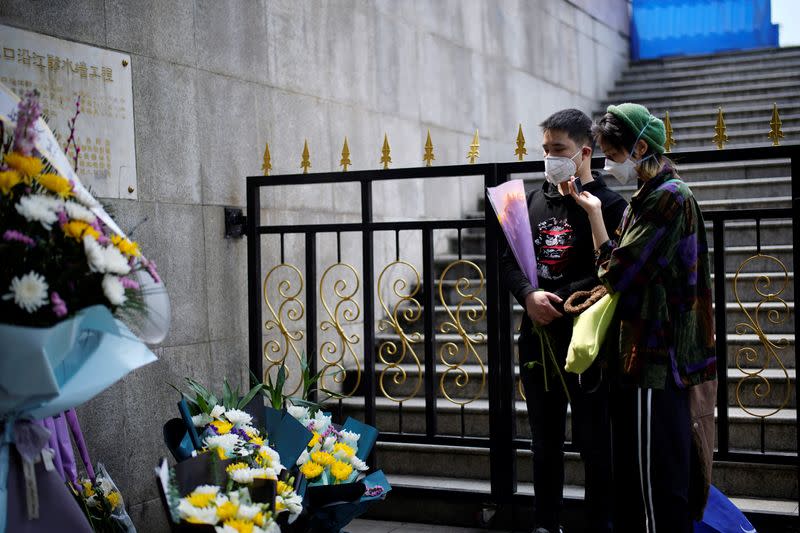 People wearing face masks pay tribute to the deceased in Wuhan