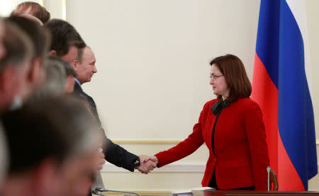 Presidential aide Elvira Nabiullina (R) shakes hands with Russia's President Vladimir Putin during a meeting on issues of fuel and energy at the Novo-Ogaryovo state residence outside Moscow, Russia, February 13, 2013. REUTERS/Sergei Karpukhin/File Photo