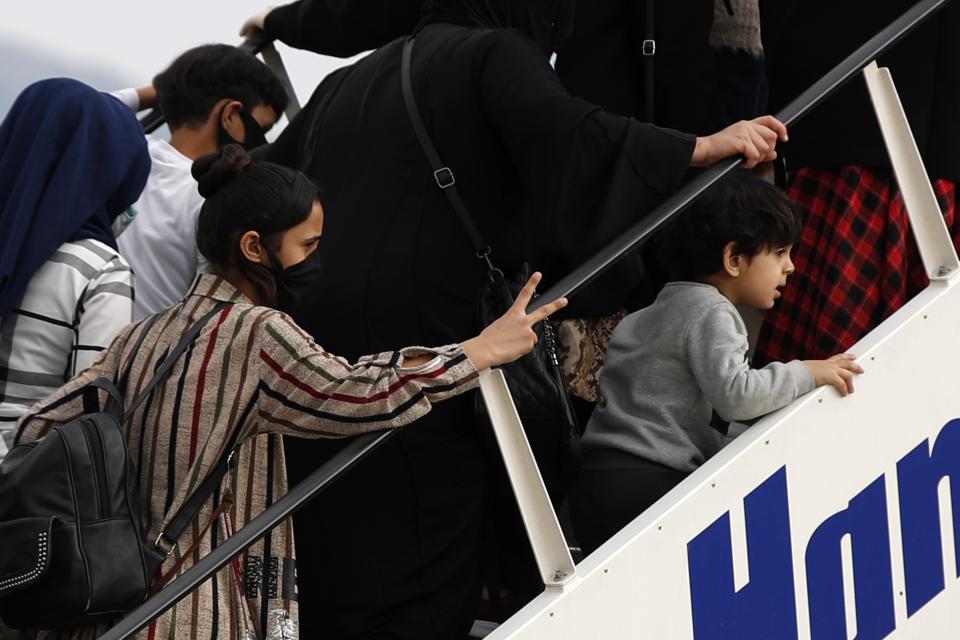 Migrants wearing face masks to prevent the spread of the coronavirus, board an airplane bound for Britain at the Eleftherios Venizelos International Airport in Athens, on Monday, May 11, 2020. Sixteen unaccompanied children refugees and 34 migrants were relocated as part of a migrant reunification plan agreed between the two countries. (AP Photo/Thanassis Stavrakis)