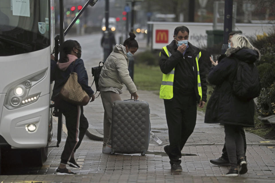 A coach delivers passengers to the Radisson Blu Edwardian Hotel, near Heathrow Airport, London, Monday Feb. 15, 2021 where they will remain during a 10 day quarantine period after returning to England from one of 33 "red list" countries. New regulations now in force require anyone who has been in a 'high-risk' location to enter England through a designated port and have pre-booked a package to stay at one of the Government's managed quarantine facilities. (Steve Parsons/PA via AP)