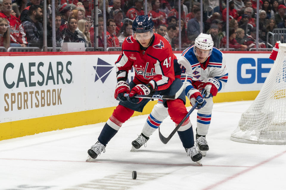 Washington Capitals left wing Beck Malenstyn (47) chases down the puck in front of New York Rangers center Riley Nash (18) during the second period of an NHL hockey game, Saturday, Dec. 9, 2023, in Washington. (AP Photo/Stephanie Scarbrough)