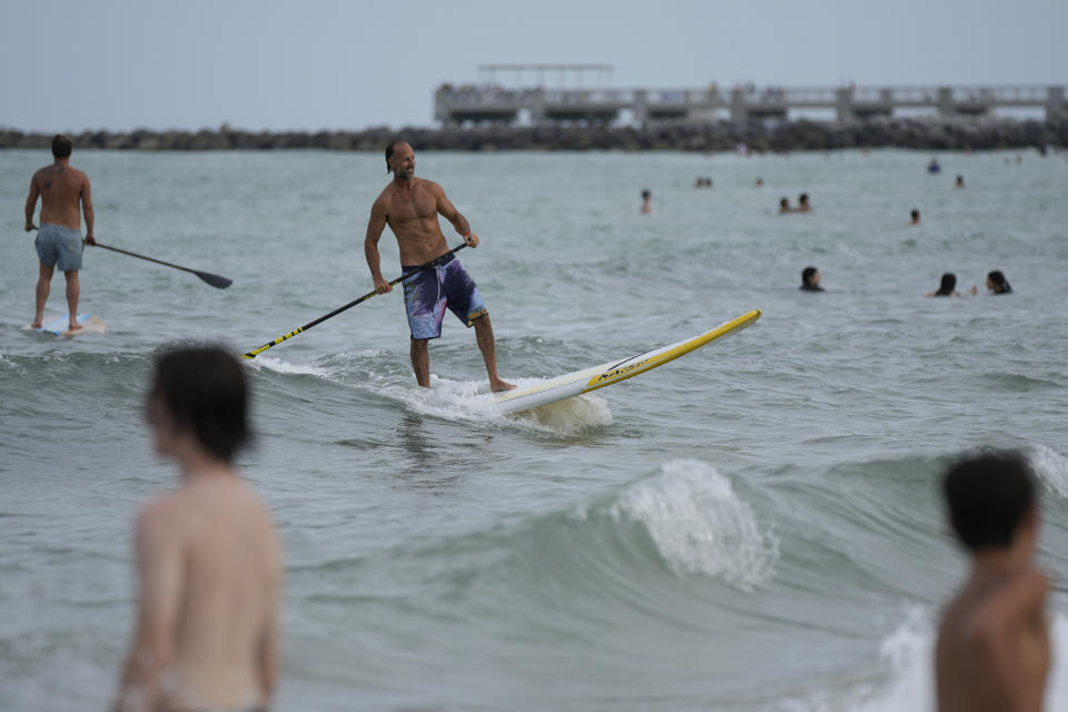 Graziano La Grasta, a local contractor and paddle board enthusiast, rides a small wave in South Beach, Friday, July 28, 2023, in Miami Beach, Fla. Humans naturally look to water for a chance to refresh, but when water temperatures get too high, some of the appeal is lost. (AP Photo/Rebecca Blackwell)