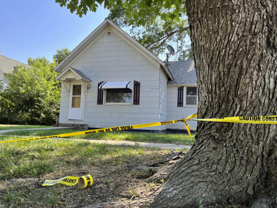 A police tape hangs on a tree outside the home of 53-year-old Michele Ebeling, Friday, Aug. 5, 2022, in Laurel, Neb. Ebeling was among four people found dead Thursday in two burning homes in this small community in northeastern Nebraska, authorities said. Police investigating the killings have arrested a neighbor of the victims, the Nebraska State Patrol said Friday. (AP Photo/Margery A. Beck)