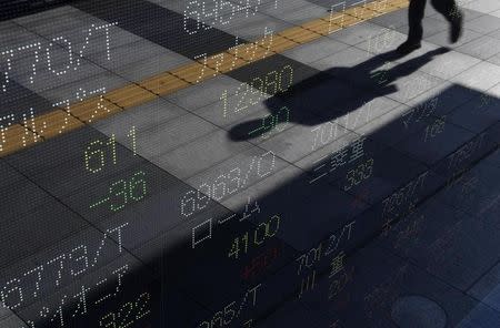 A shadow of a passerby is reflected on an electronic board displaying stock prices outside a brokerage in Tokyo October 31, 2011. REUTERS/Issei Kato