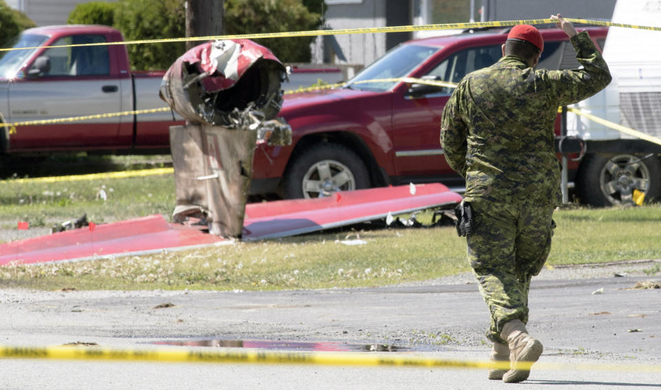 A member of the Canadian Forces walks past the tail section of a Snowbird jet in Kamloops, British Columbia, Monday, May 18, 2020. Capt. Jennifer Casey died Sunday after the Snowbirds jet she was in crashed shortly after takeoff. The pilot of the aircraft is in hospital with serious injuries. (Jonathan Hayward/The Canadian Press via AP)