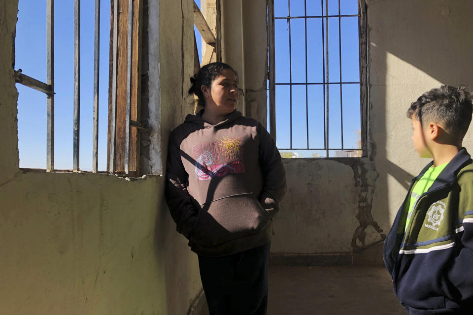 In this Jan. 11, 2020, photo, Enma Floriana chats with her 13-year-old son in the stairway of a migrant shelter in Mexicali, Mexico. The Guatemalan family is seeking asylum in a San Diego immigration court. Illegal border crossings have plummeted as the Trump administration has extended a policy to make asylum seekers wait in Mexico for court hearings in the U.S. (AP Photo/Elliot Spagat)