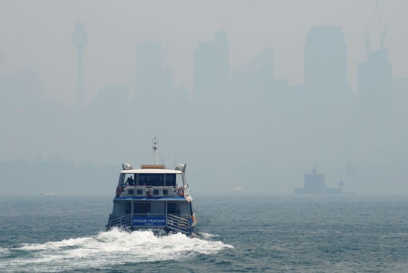 A ferry makes its way from Taronga Zoo to Circular Quay, with the CBD skyline barely visible in the background through smoke haze from bushfires, in Sydney Harbour