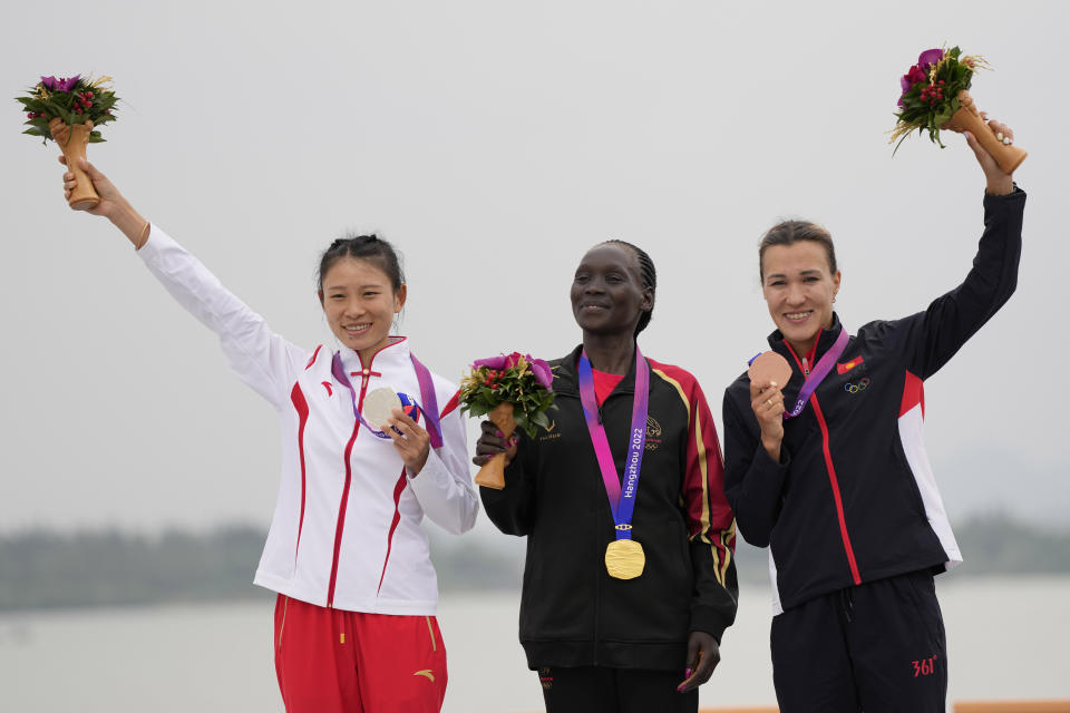 From left, silver China's Zhang Deshun, gold medalist Bahrain's Eunice Chebichii Paul Chumba and bronze medalist Kyrgyztan's Sardana Trofimova celebrate on the podium during the victory ceremony for the women's marathon at the 19th Asian Games in Hangzhou, China, Thursday, Oct. 5, 2023. (AP Photo/Lee Jin-man)