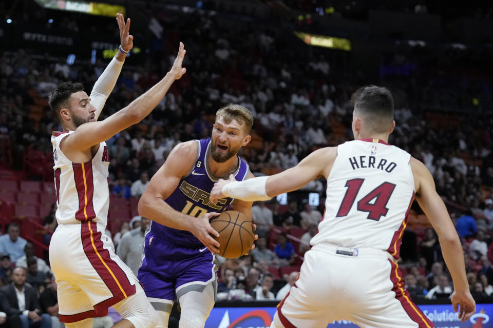 Sacramento Kings center Domantas Sabonis (10) looks for an opening past Miami Heat guards Tyler Herro (14) and Max Strus during the first half of an NBA basketball game, Wednesday, Nov. 2, 2022, in Miami. (AP Photo/Wilfredo Lee)