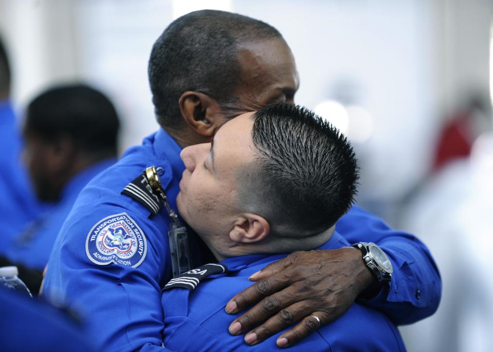 TSA personnel comfort each other before the U.S. Honor Flag arrives at Los Angeles International Airport