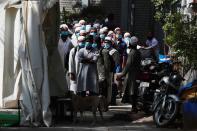 Men wearing protective masks wait for a bus that will take them to a quarantine facility, amid concerns about the spread of coronavirus disease (COVID-19), in Nizamuddin area of New Delhi