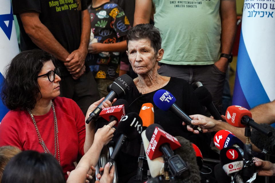 A women speaks into a bank of microphones.