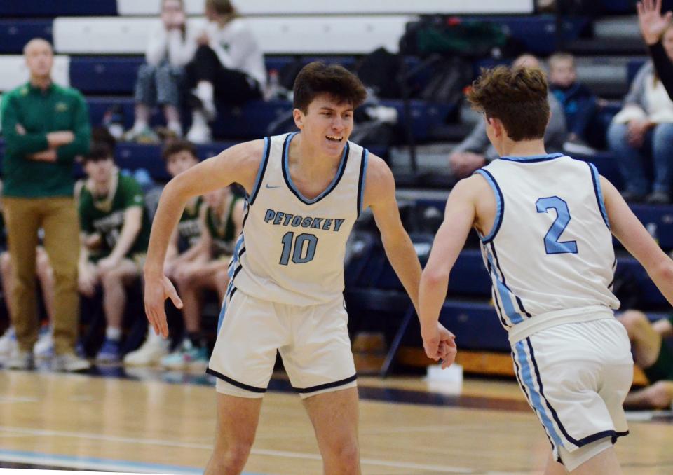 Petoskey's Jimmy Marshall (10) and Brady Odenbach (2) celebrate a basket during the second half that increased the Northmen lead against visiting TC West.