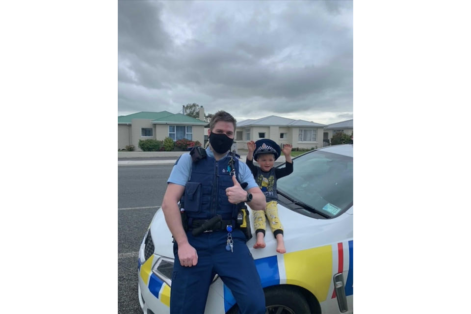 In this photo released by New Zealand Police, an officer identified only as Constable Kurt sits on his patrol car with a 4-year-old boy who is not identified, in the South Island city of Invercargill, New Zealand, Friday, Oct. 15, 2021. An emergency call made by the 4-year-old New Zealand boy asking for police to come over and check out his toys prompted a real-life callout and confirmation from an officer that the toys were, indeed, pretty cool. (NZ Police via AP)