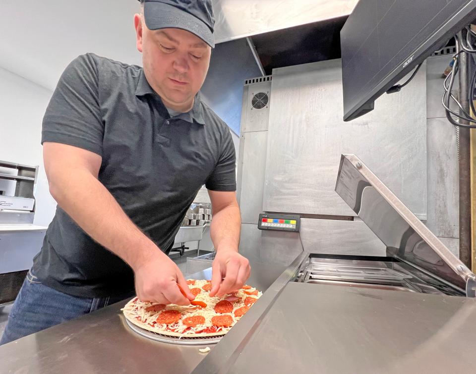 John Bell creates a pizza at his new venture, reviving the former KD Pizza & Subs on Marion Avenue.