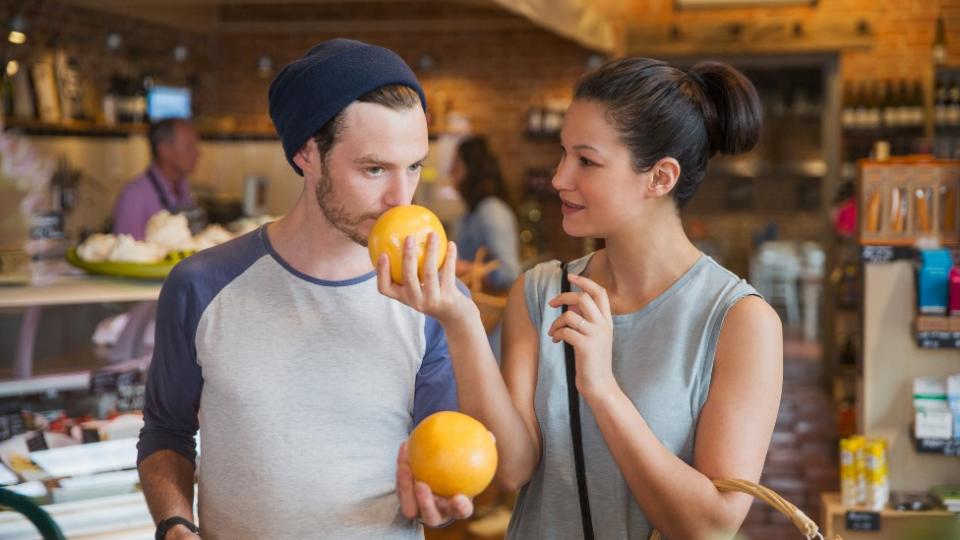 Una pareja oliendo pomelos en un mercado